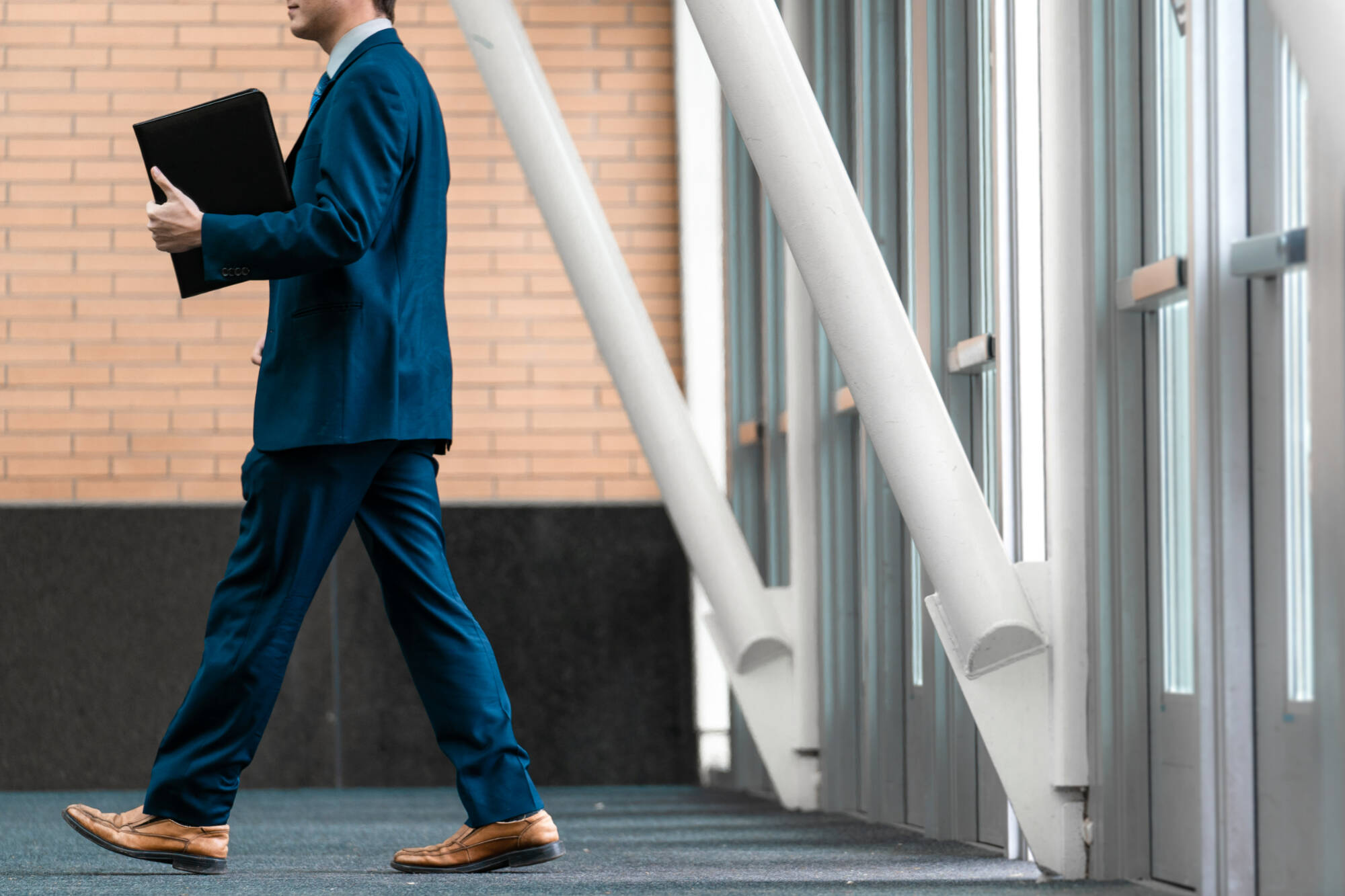 Masculine person holding a portfolio in motion.